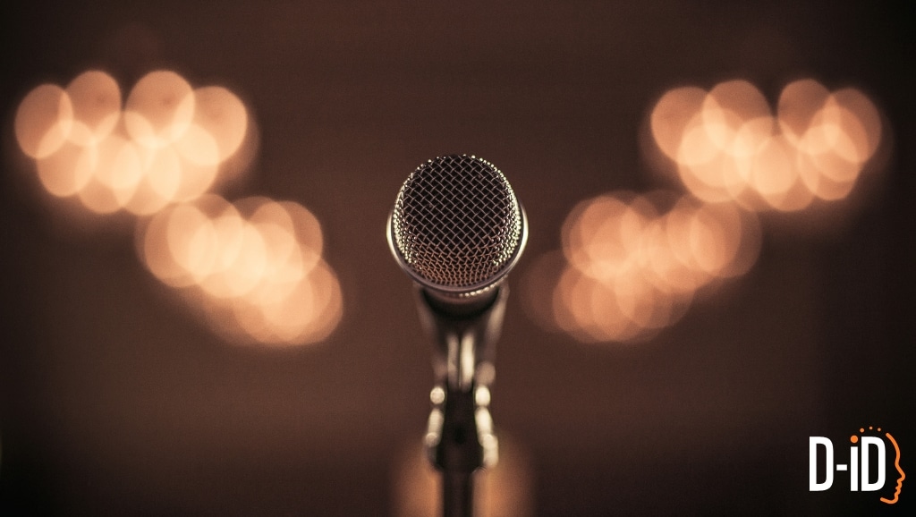 A close-up of a microphone on a stand with blurred, warm lights in the background and the D-ID logo in the lower right corner, evoking the innovative power of AI Voice technology.
