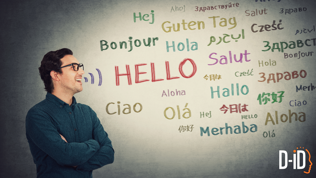 A man with glasses smiles while looking at the word "Hello" and its translations in various languages on a wall, highlighting real time speech translation. D-ID logo appears in the bottom right corner.